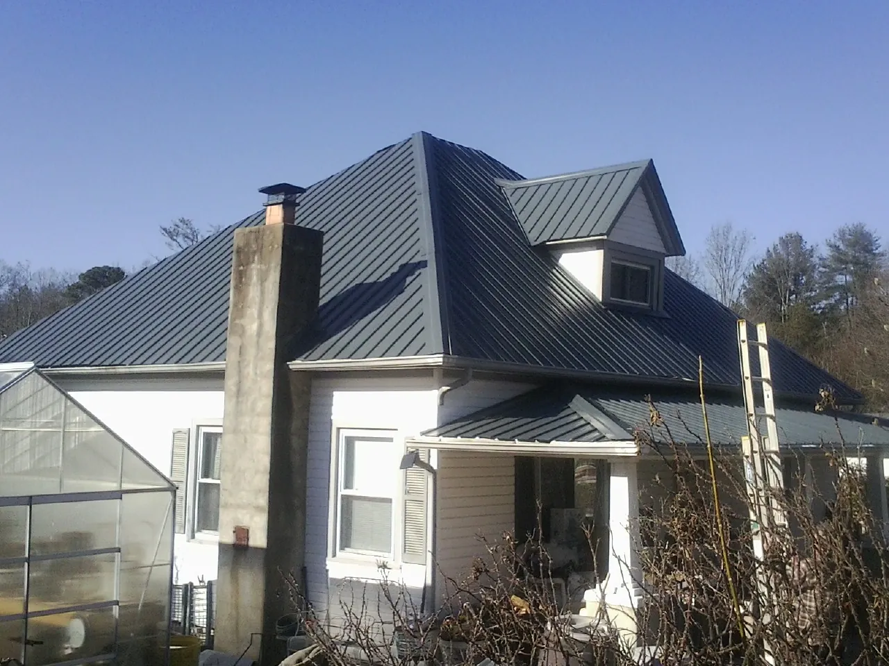 Dark blue standing seam metal roof on a white farmhouse with dormer — Slate & Tile Roof Repair by Roofing Brothers in Sadieville