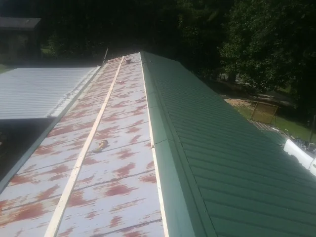 Old rusted panels beside newly installed green metal roofing — Wind Damage Roof Repair by Roofing Brothers in Sadieville