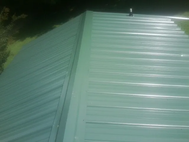 New green metal panels meeting at the ridge of a roof — Flat Roof Repair work by our crew in Sadieville