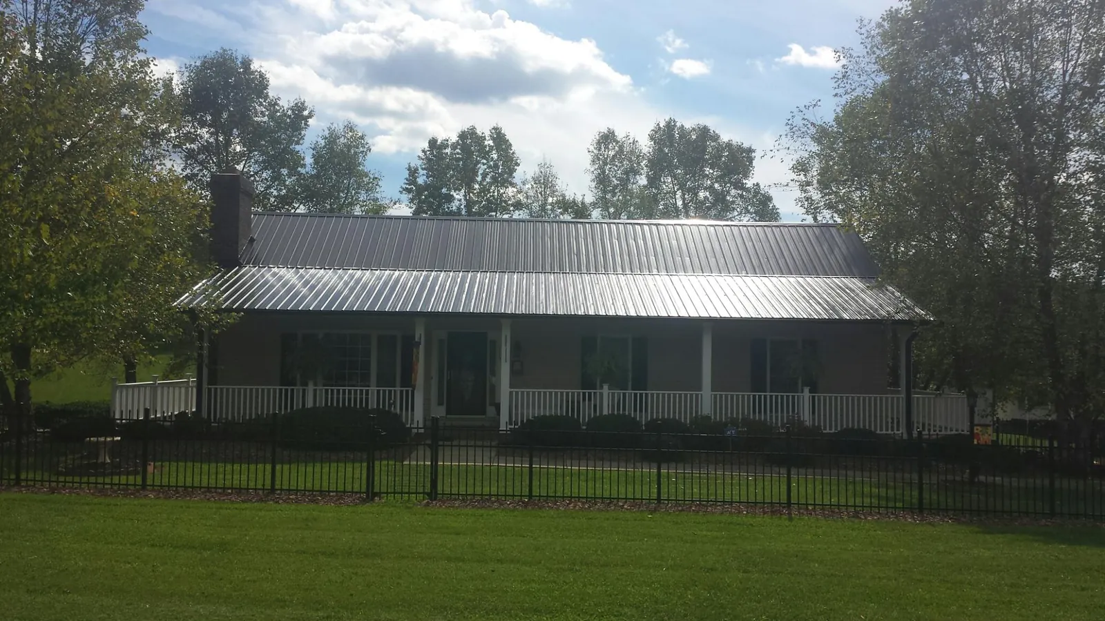 Gray metal roof on a brick ranch with a full width front porch — Gutter Guard Installation work by our crew in Sadieville