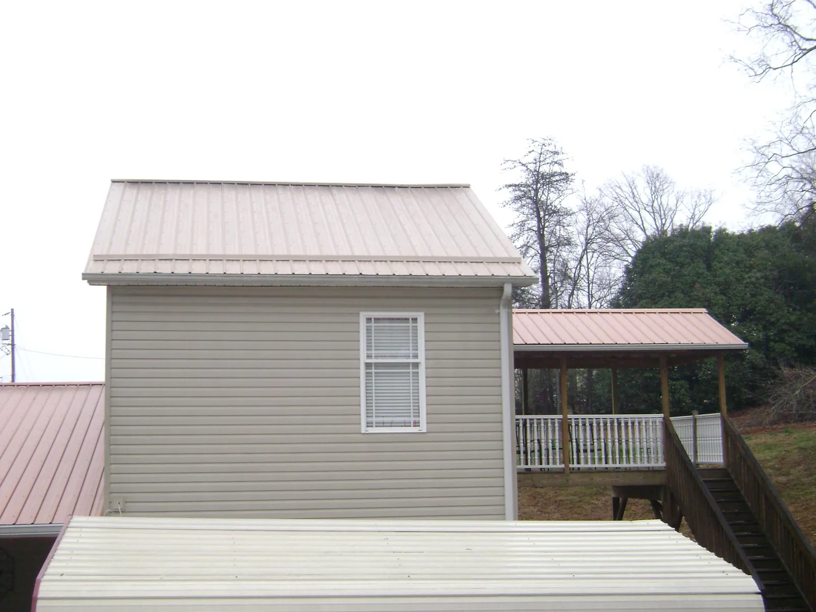 Tan metal roofs on a two story addition and attached porch, from a Roof Replacement job in Sadieville