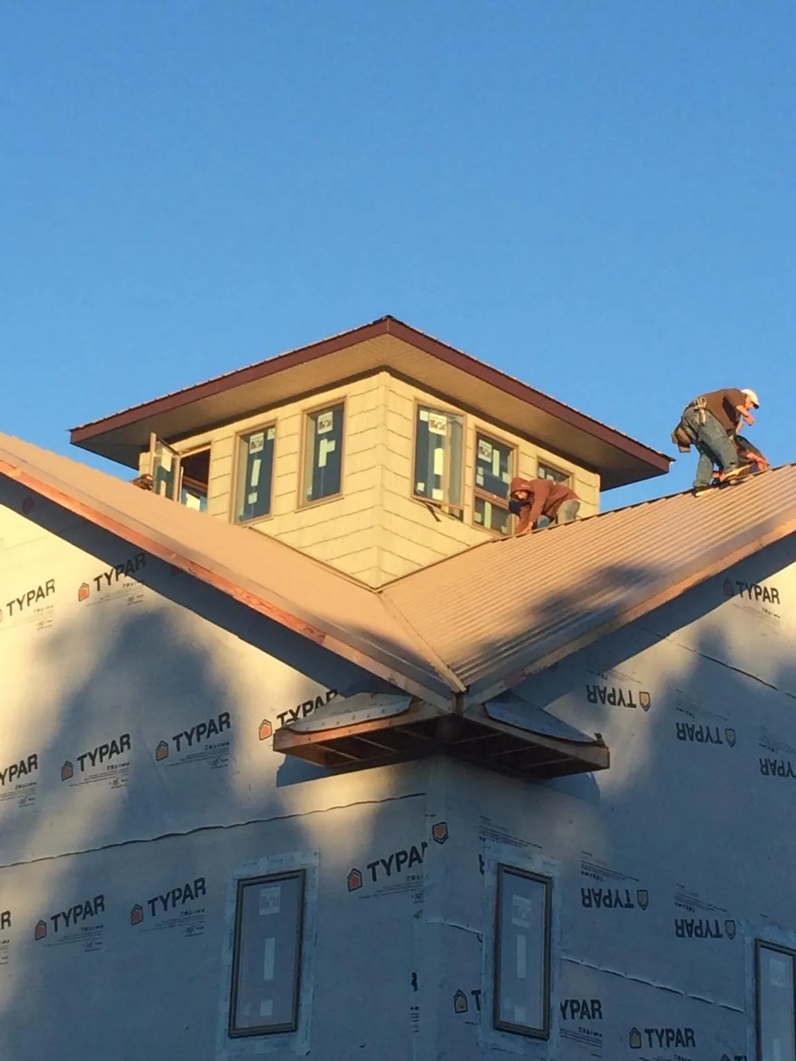 Roofers working around a rooftop cupola on a new metal roof at sunset — Roof Waterproofing in Sadieville by Roofing Brothers